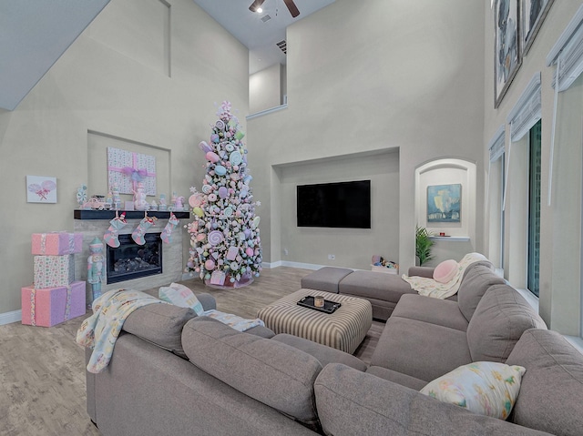 living room featuring ceiling fan, hardwood / wood-style floors, and a high ceiling