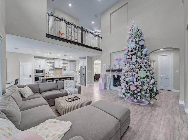 living room featuring light hardwood / wood-style flooring, a towering ceiling, and a notable chandelier