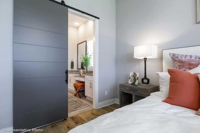 bedroom featuring a barn door, dark wood-type flooring, and connected bathroom