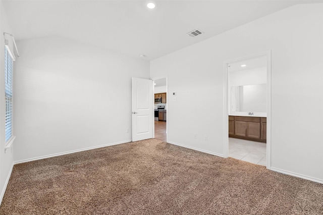 unfurnished bedroom featuring light colored carpet and connected bathroom