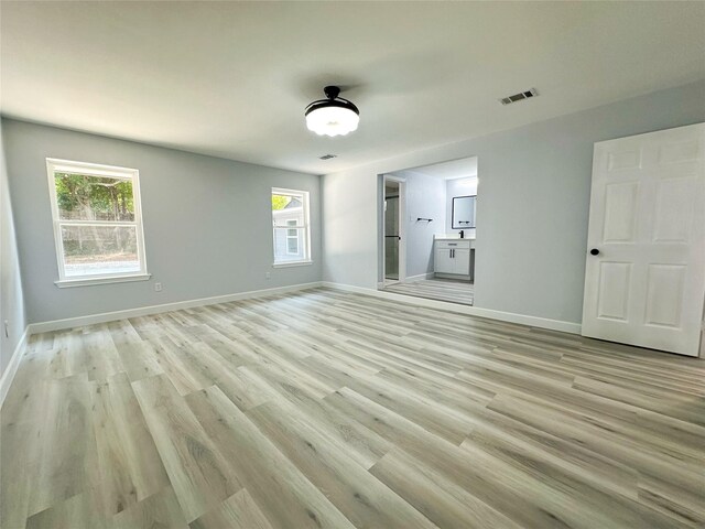 unfurnished bedroom with light hardwood / wood-style floors and ensuite bathroom