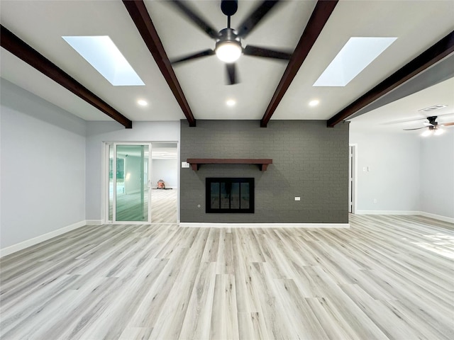 unfurnished living room with light hardwood / wood-style flooring, a brick fireplace, beamed ceiling, and ceiling fan