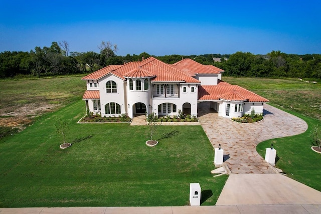 mediterranean / spanish house with driveway, a tile roof, a front lawn, and stucco siding