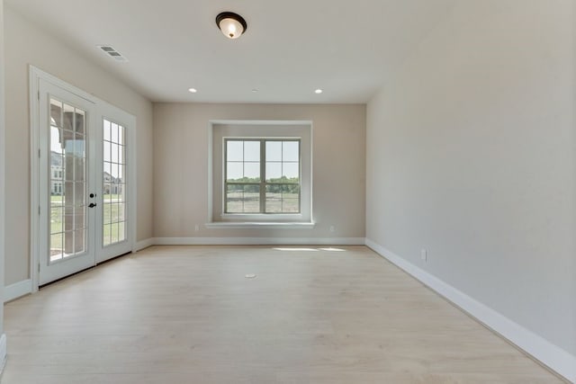 spare room featuring french doors, plenty of natural light, and light wood-type flooring