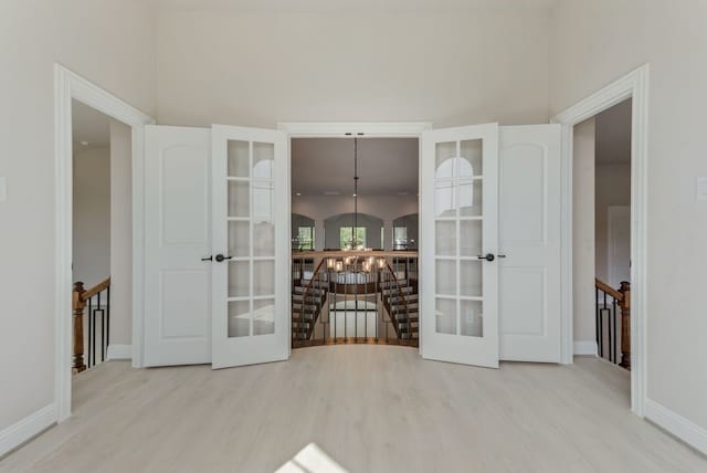 unfurnished room with light hardwood / wood-style flooring, an inviting chandelier, and french doors