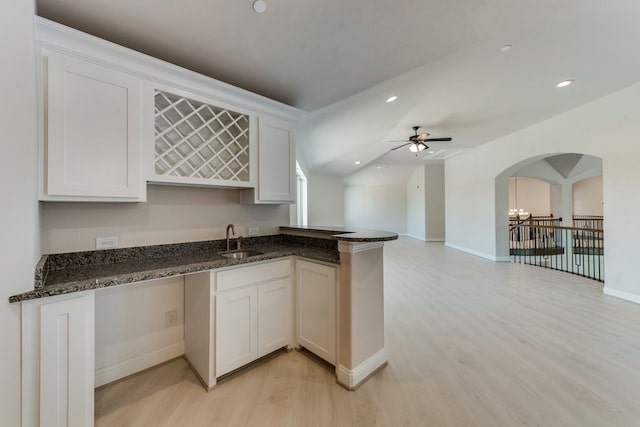 kitchen with sink, light hardwood / wood-style flooring, white cabinets, and dark stone counters