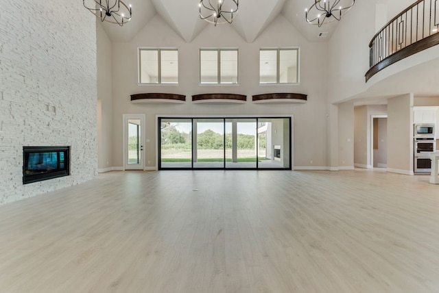 unfurnished living room with a notable chandelier, light hardwood / wood-style floors, and a high ceiling