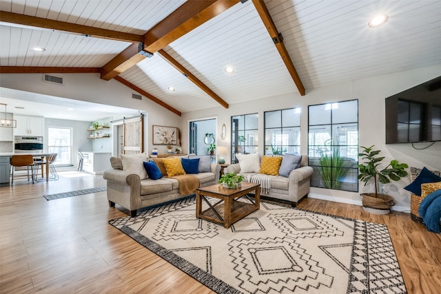 living room with a barn door, vaulted ceiling with beams, and light wood-type flooring