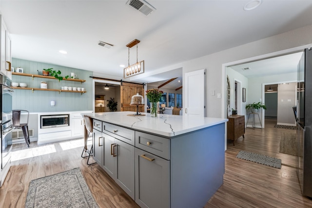 kitchen with hanging light fixtures, a breakfast bar area, light hardwood / wood-style floors, and a center island