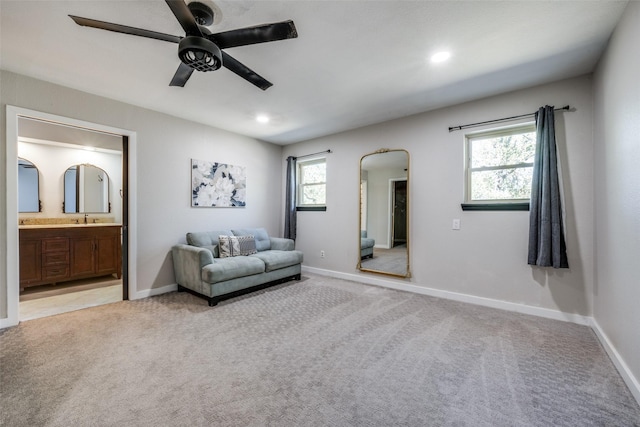 living area with sink, a wealth of natural light, light colored carpet, and ceiling fan