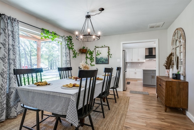 dining space with an inviting chandelier and light hardwood / wood-style flooring