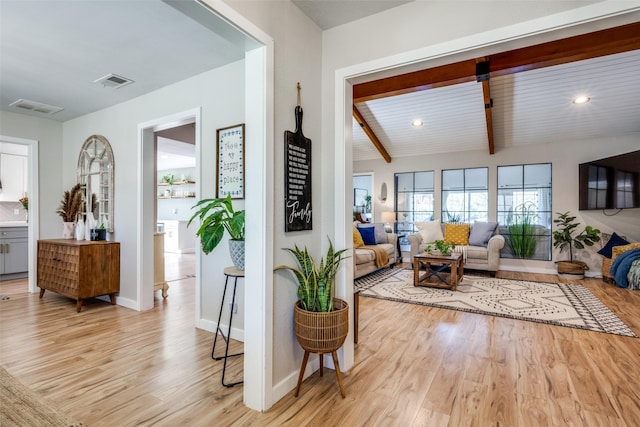 living room featuring beamed ceiling and light hardwood / wood-style flooring