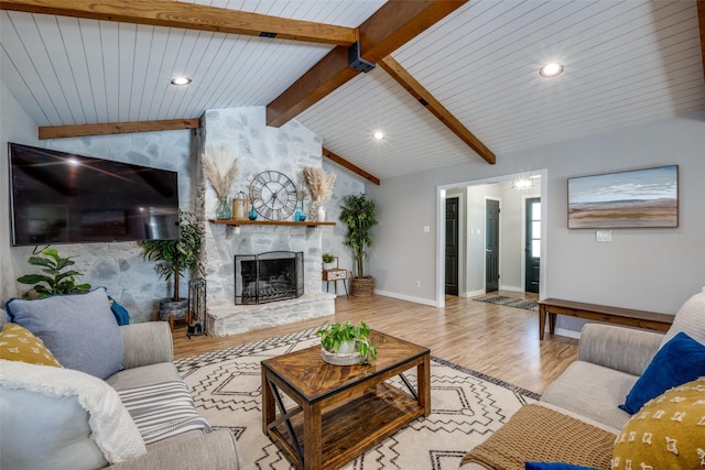 living room featuring vaulted ceiling with beams, a fireplace, and light hardwood / wood-style floors