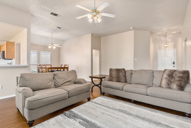 living room with ceiling fan, dark hardwood / wood-style floors, lofted ceiling, and a textured ceiling