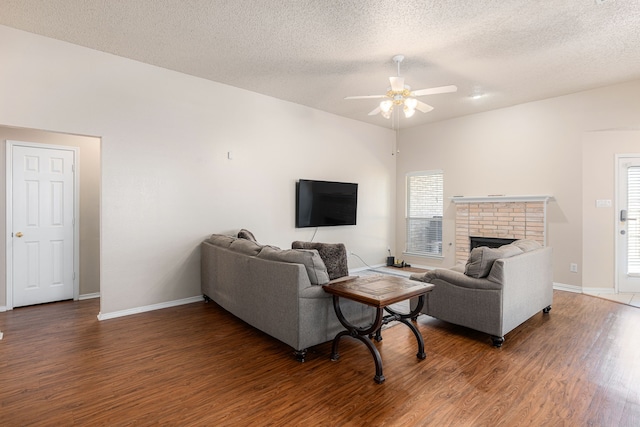 living room featuring a fireplace, ceiling fan, dark hardwood / wood-style flooring, and a textured ceiling