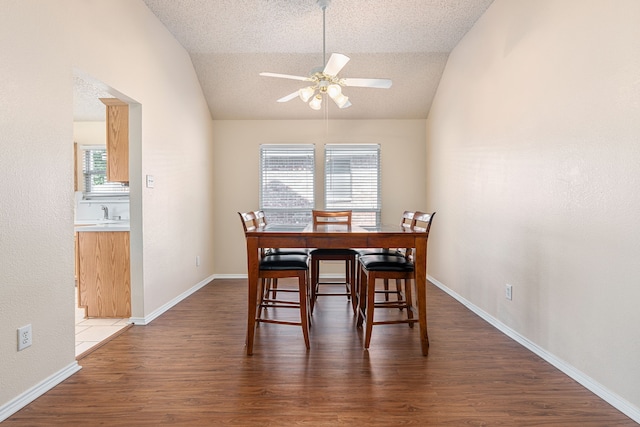 dining room featuring a textured ceiling, ceiling fan, lofted ceiling, and dark wood-type flooring