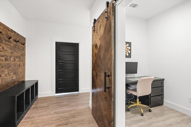 office space featuring a barn door and light hardwood / wood-style flooring