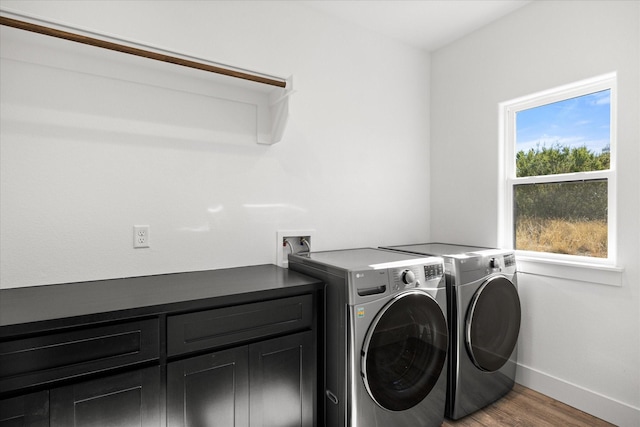 laundry room with washer and dryer, hardwood / wood-style flooring, and cabinets