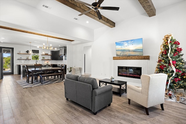 living room featuring beamed ceiling and ceiling fan with notable chandelier