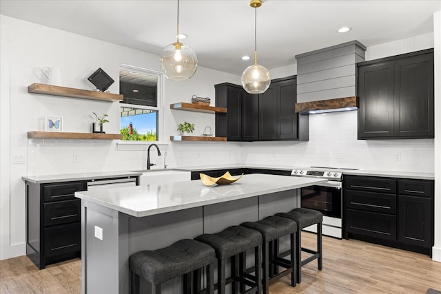 kitchen with sink, a breakfast bar, hanging light fixtures, a center island, and light wood-type flooring