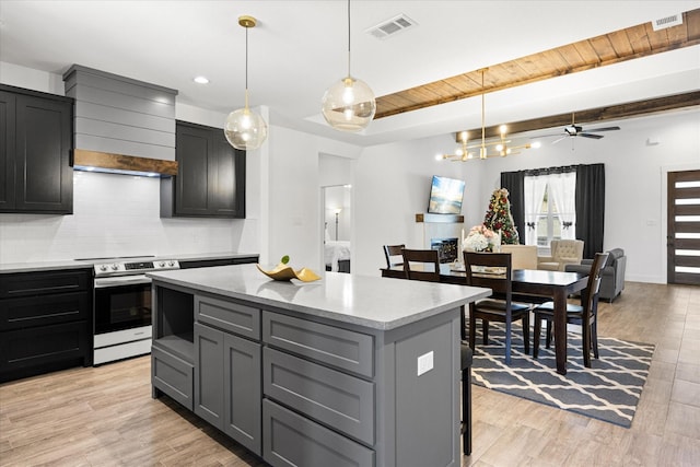 kitchen with a kitchen island, decorative light fixtures, stainless steel range with electric cooktop, backsplash, and light hardwood / wood-style floors