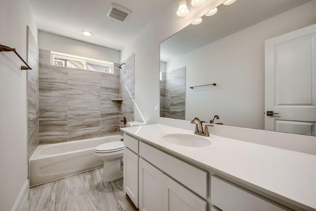 full bathroom featuring tiled shower / bath, vanity, and toilet