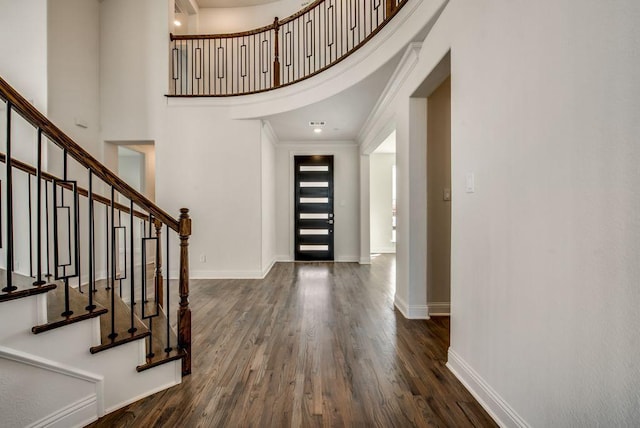 entrance foyer with hardwood / wood-style floors, ornamental molding, and a high ceiling