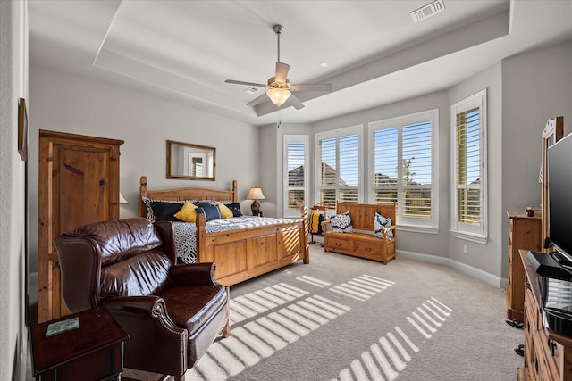 carpeted bedroom with a tray ceiling and ceiling fan