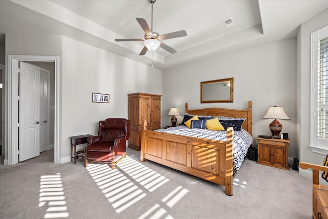 carpeted bedroom featuring a raised ceiling and ceiling fan