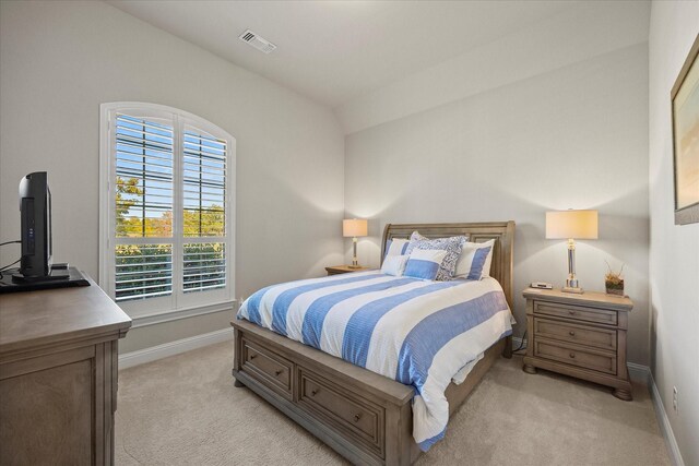 bedroom with light carpet and lofted ceiling