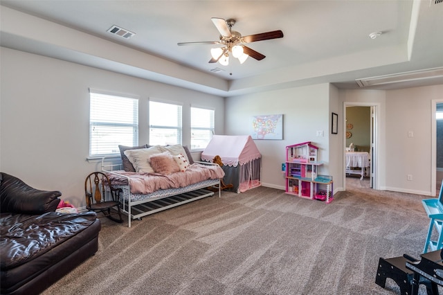 bedroom with carpet flooring, ceiling fan, and a tray ceiling