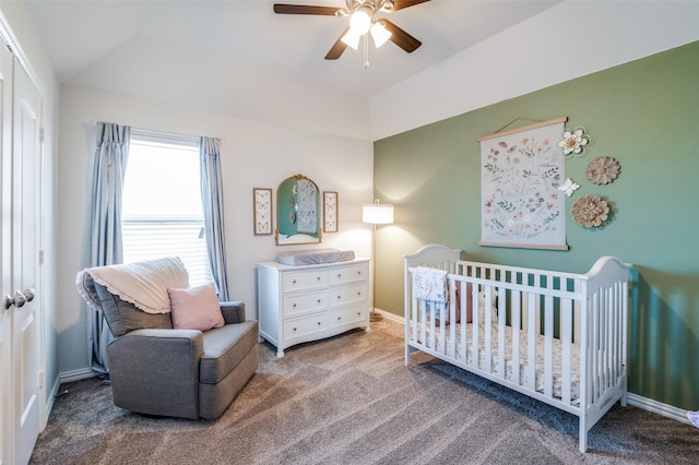 carpeted bedroom featuring vaulted ceiling, ceiling fan, a closet, and a crib