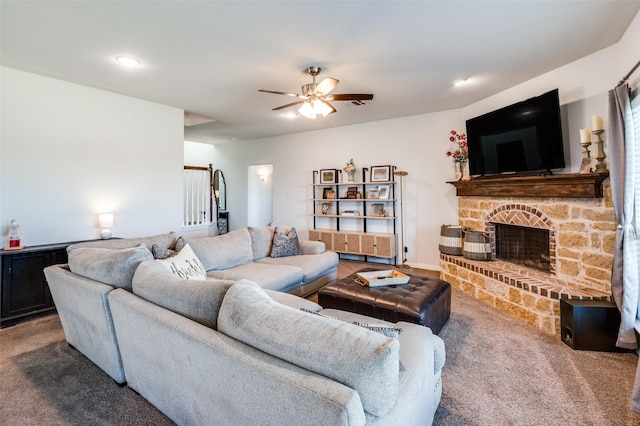 carpeted living room with ceiling fan and a stone fireplace