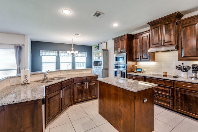 kitchen with a center island, an inviting chandelier, appliances with stainless steel finishes, decorative light fixtures, and dark brown cabinets