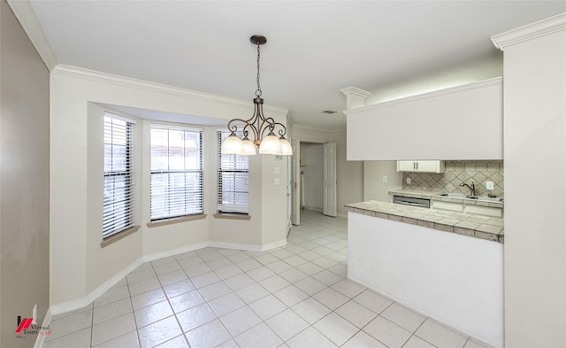 kitchen with an inviting chandelier, decorative light fixtures, decorative backsplash, white cabinets, and ornamental molding