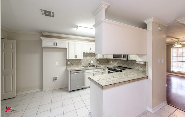 kitchen with stainless steel appliances, light tile patterned floors, backsplash, kitchen peninsula, and white cabinets