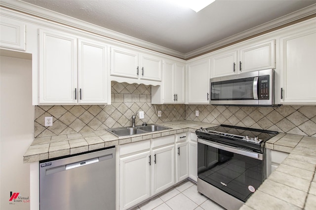 kitchen featuring tile counters, sink, backsplash, white cabinets, and appliances with stainless steel finishes