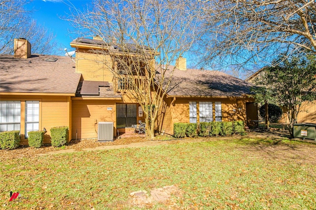 rear view of property featuring central air condition unit and a lawn