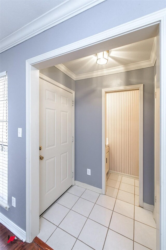 foyer entrance with ornamental molding and light tile patterned floors