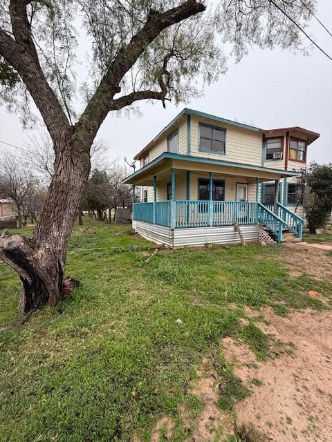 rear view of house featuring covered porch and a lawn