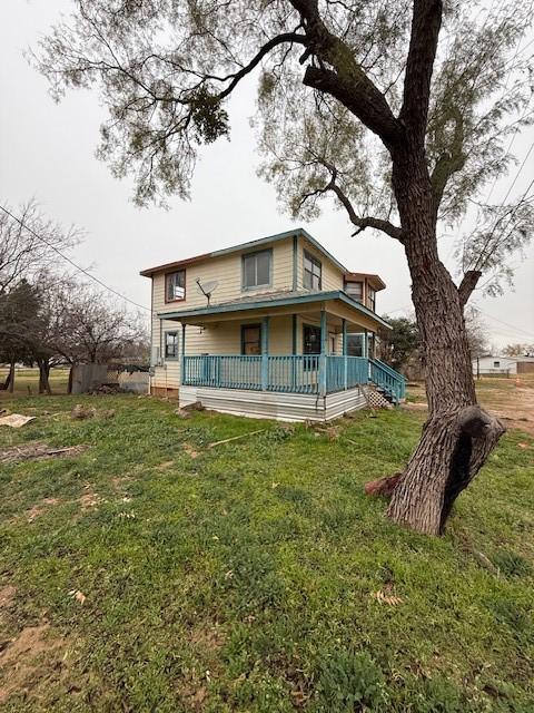 rear view of property featuring a lawn and a porch