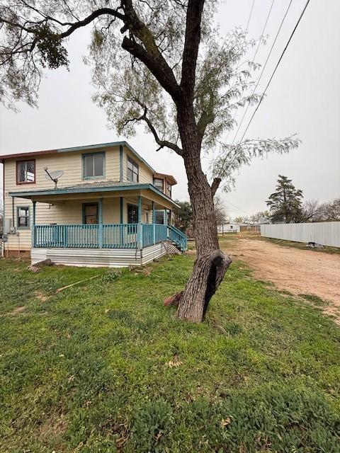 rear view of property featuring a porch and a lawn