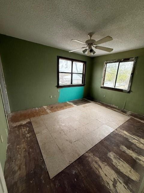 unfurnished room featuring a wealth of natural light, a textured ceiling, and ceiling fan