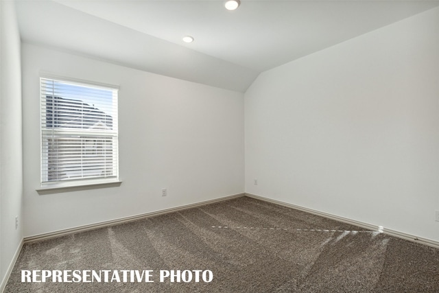 spare room featuring carpet flooring and vaulted ceiling