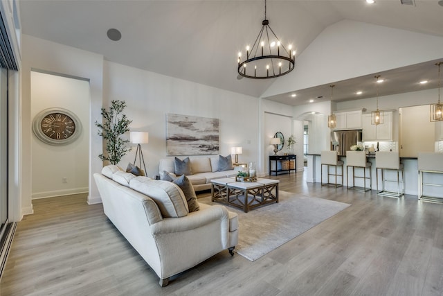 living room featuring a chandelier, vaulted ceiling, and light hardwood / wood-style flooring