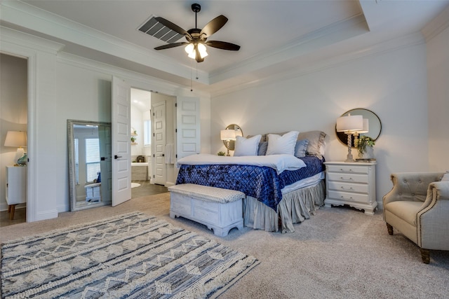 carpeted bedroom with ceiling fan, crown molding, ensuite bathroom, and a tray ceiling