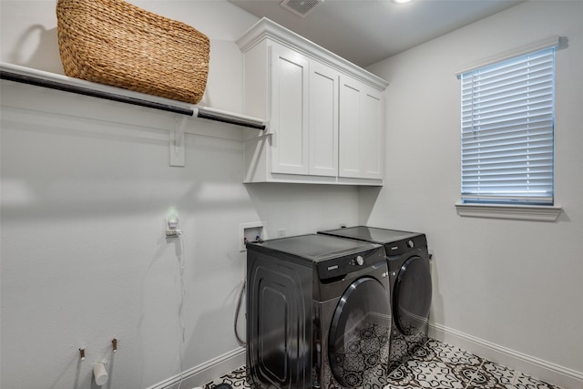 clothes washing area featuring washing machine and clothes dryer, tile patterned flooring, and cabinets