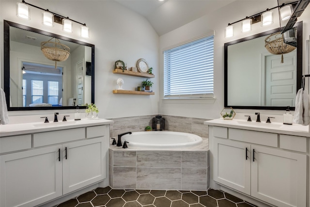 bathroom featuring tile patterned floors, a relaxing tiled tub, lofted ceiling, and vanity