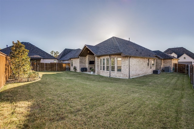 rear view of property with a yard and central AC unit