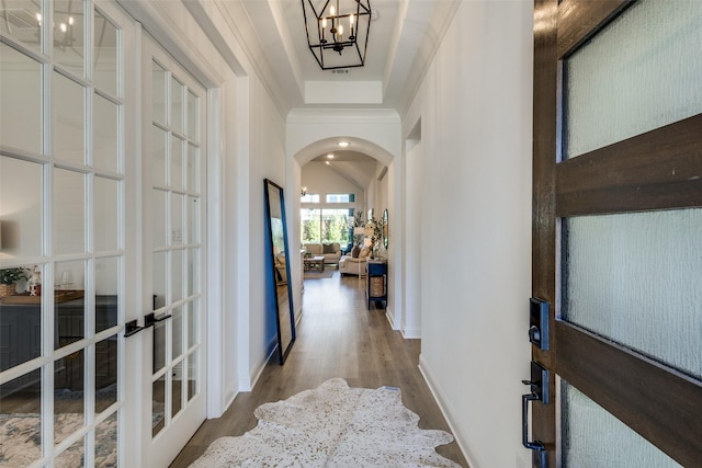 hall with a chandelier, wood-type flooring, ornamental molding, and french doors